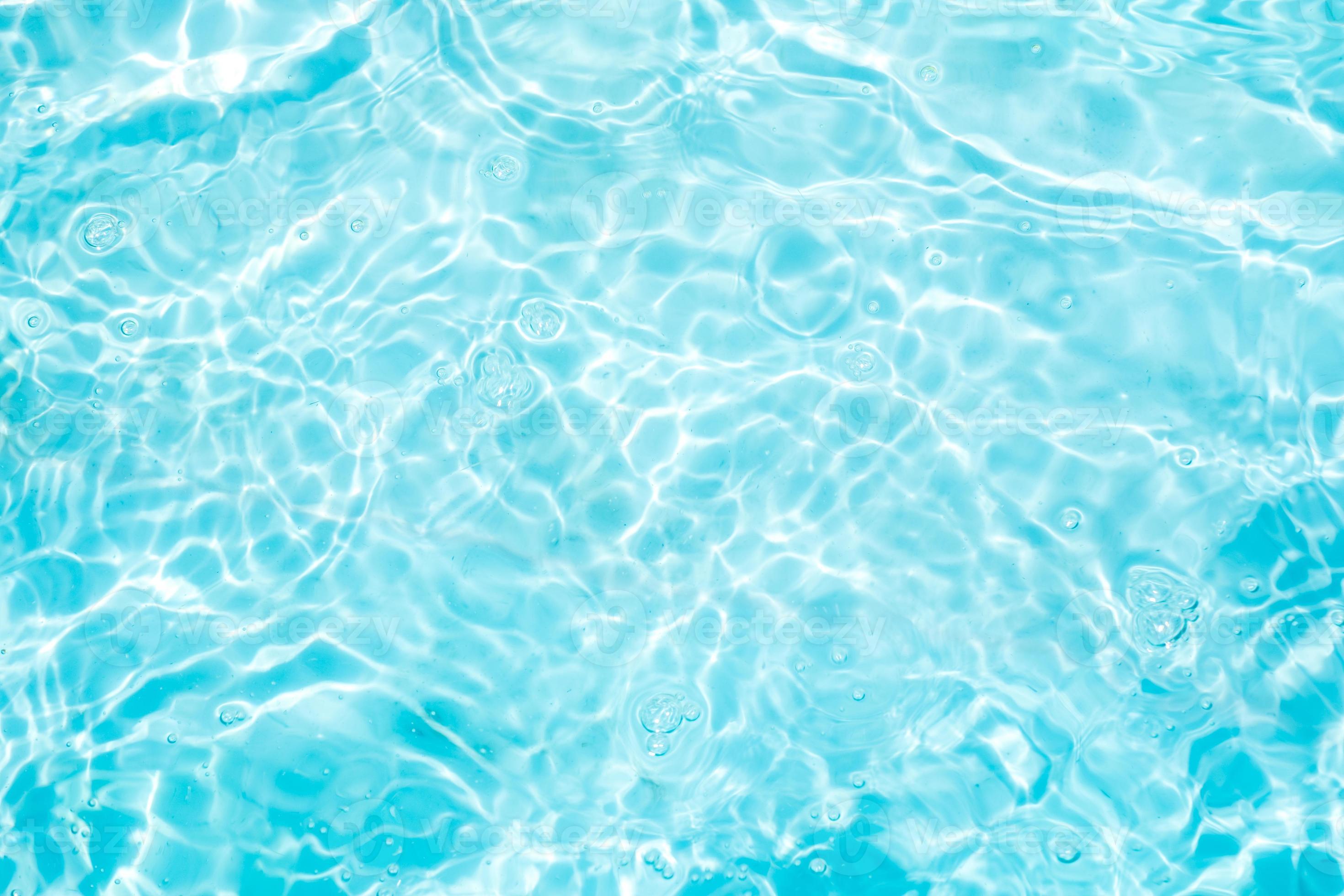 Blurred transparent blue colored clear calm water surface texture with