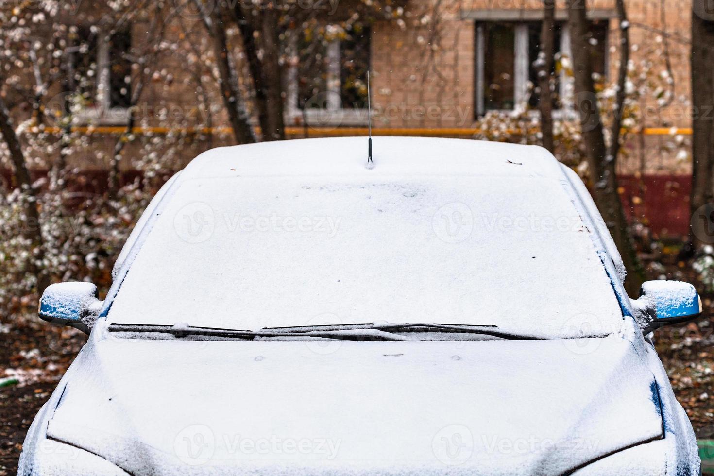 first snow on car in front of apartment house photo