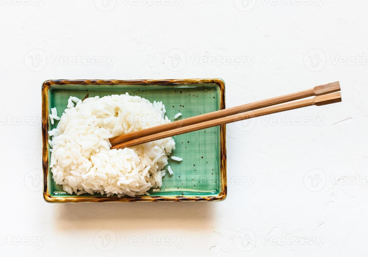 boiled rice with chopsticks on plate on white photo