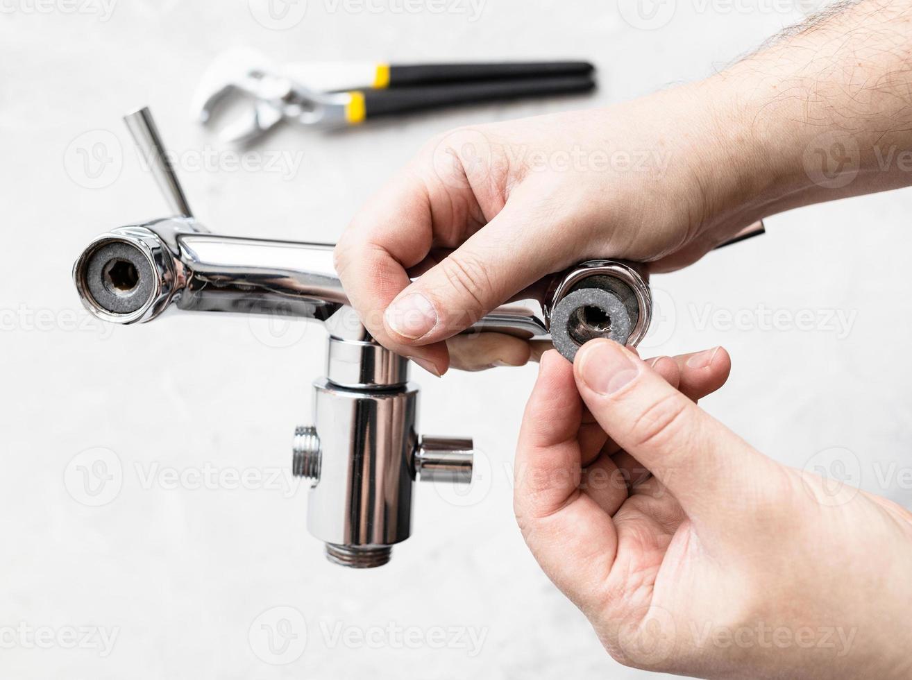 hands install paronite gasket in faucet and wrench photo