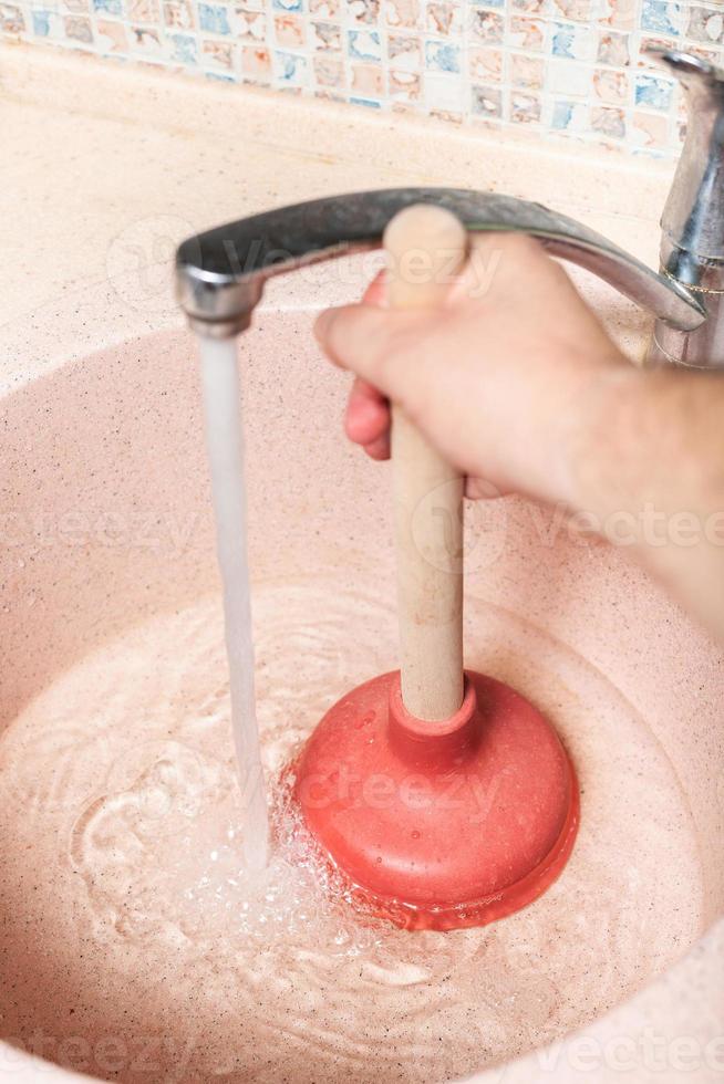 man clears kitchen sink drain by plunger photo