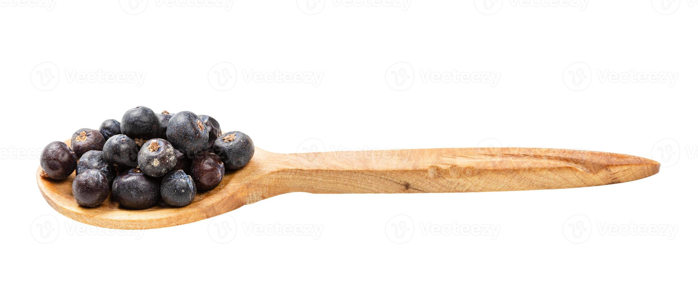 wooden spoon with dried juniper berries isolated photo