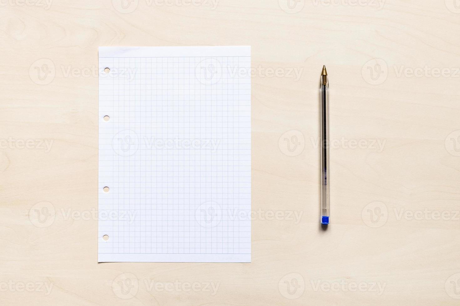 pen and blank squared paper on light board photo