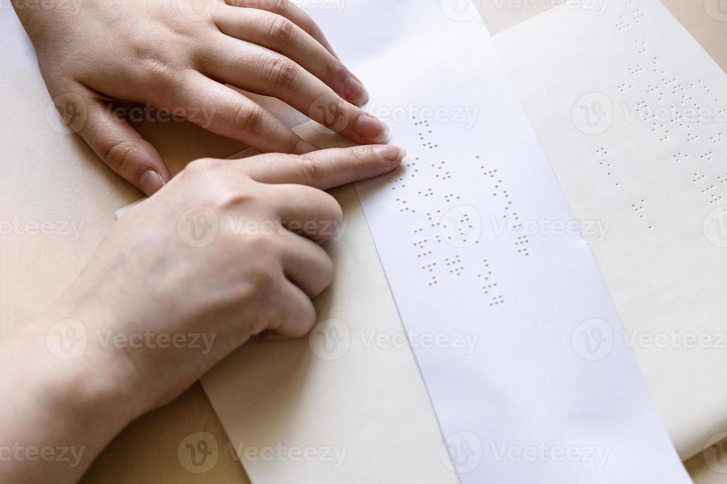 woman reads note in braille on sheet of paper photo