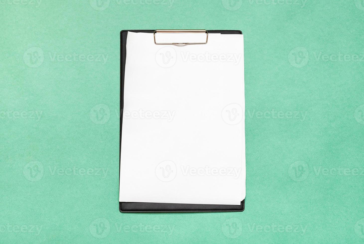 clipboard with blank white paper sheets on green photo