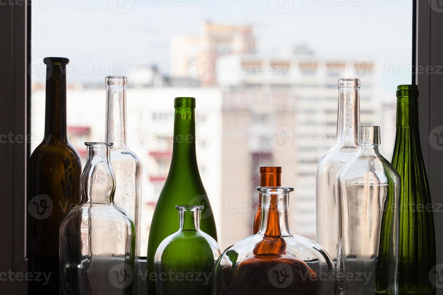 varias botellas vacías en el alféizar y vista de la ciudad foto
