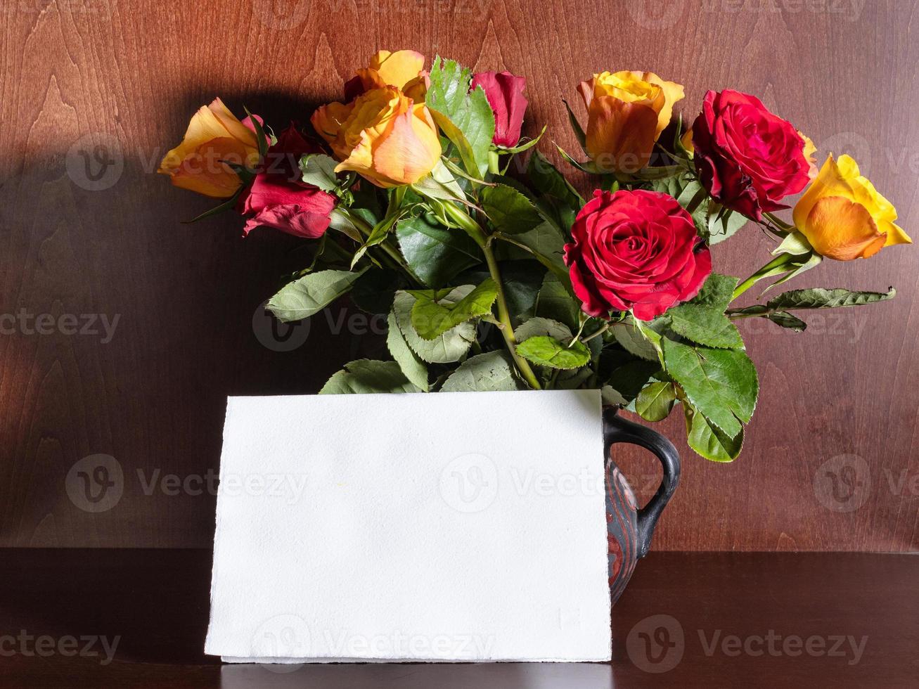 hoja de papel en blanco y rosas rojas y amarillas foto