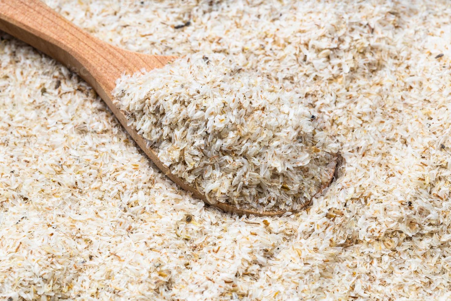 cuchara de madera con cáscara de psyllium de cerca en la pila foto