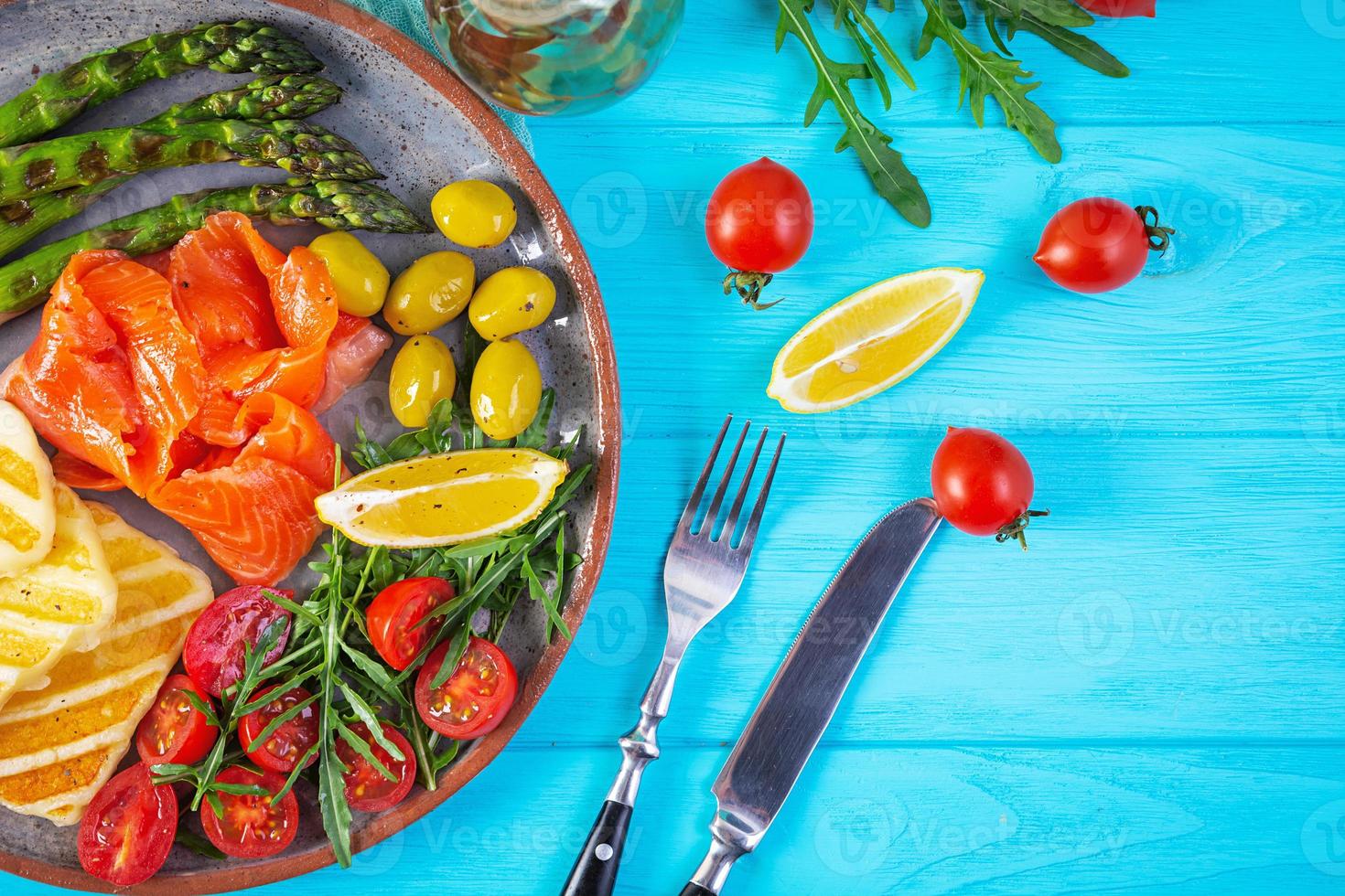 ensalada con espárragos, queso halloumi a la parrilla, filete de salmón, tomates, rúcula y aceitunas verdes. vista superior foto