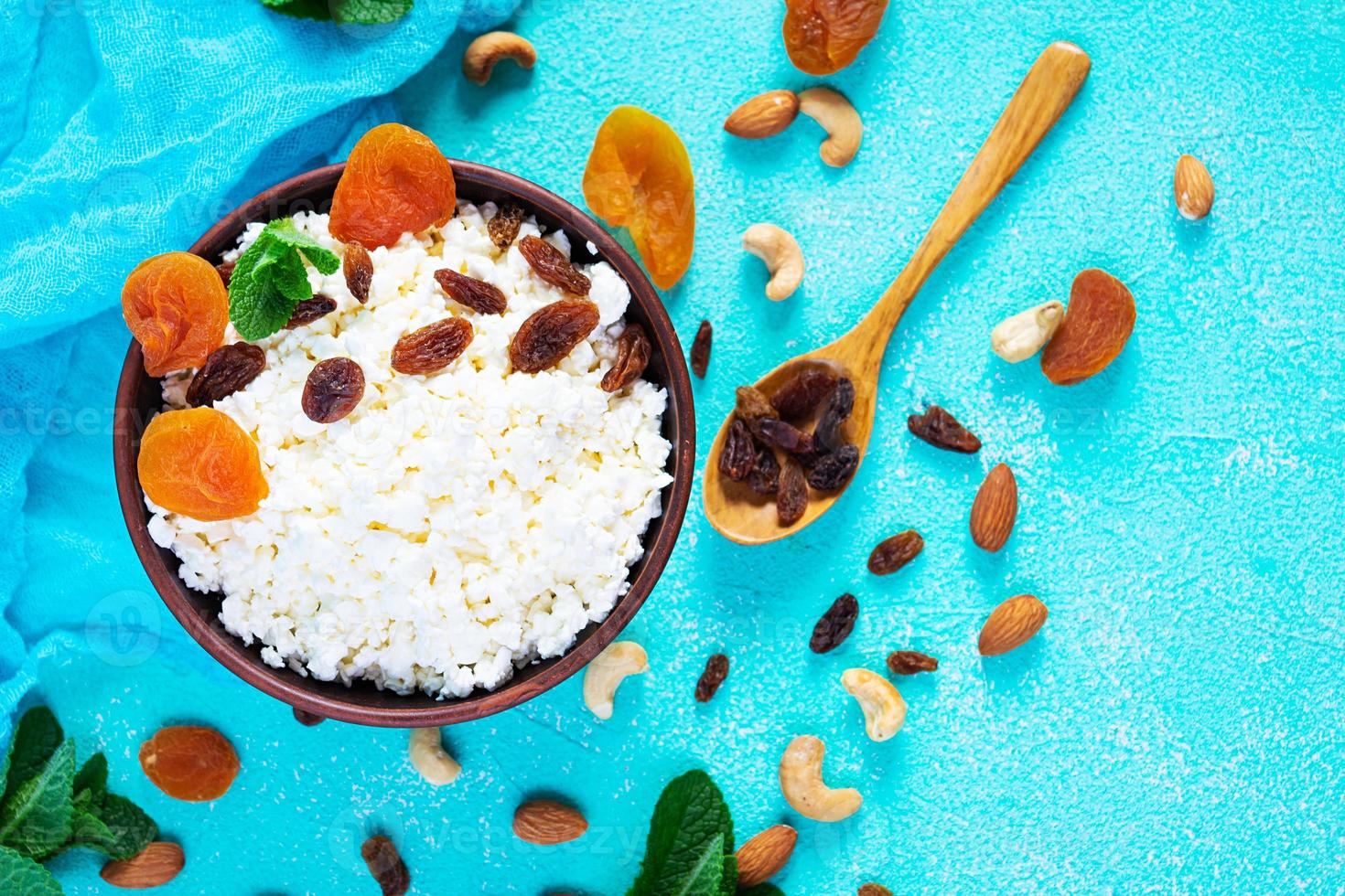 Healthy breakfast cottage cheese with raisins, dried apricots, almond, cashew and mint. Top view photo