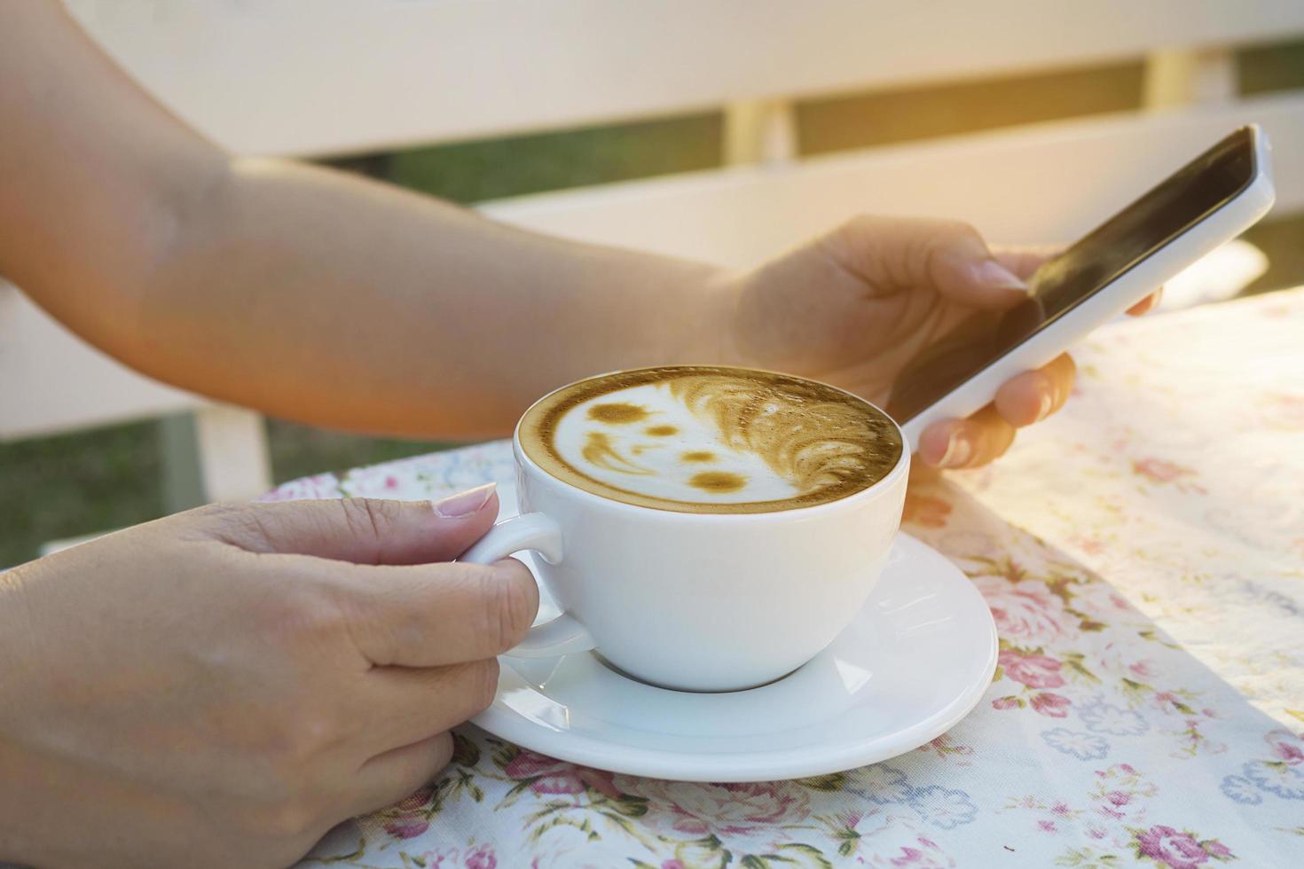 Lady using mobile white drinking coffee photo
