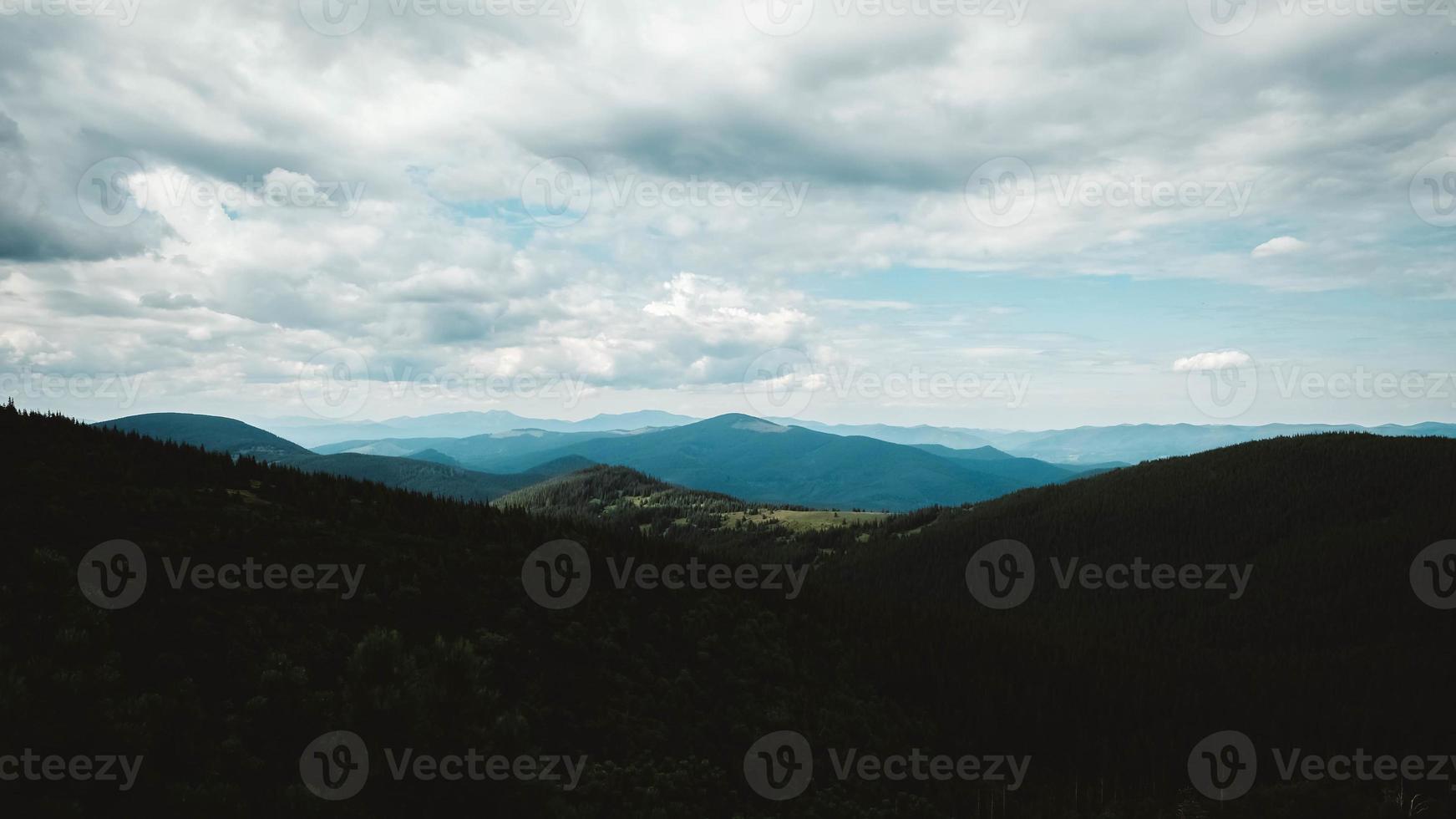 Green mountains of Carpathians in middle of forest against background of a dramatic sky photo