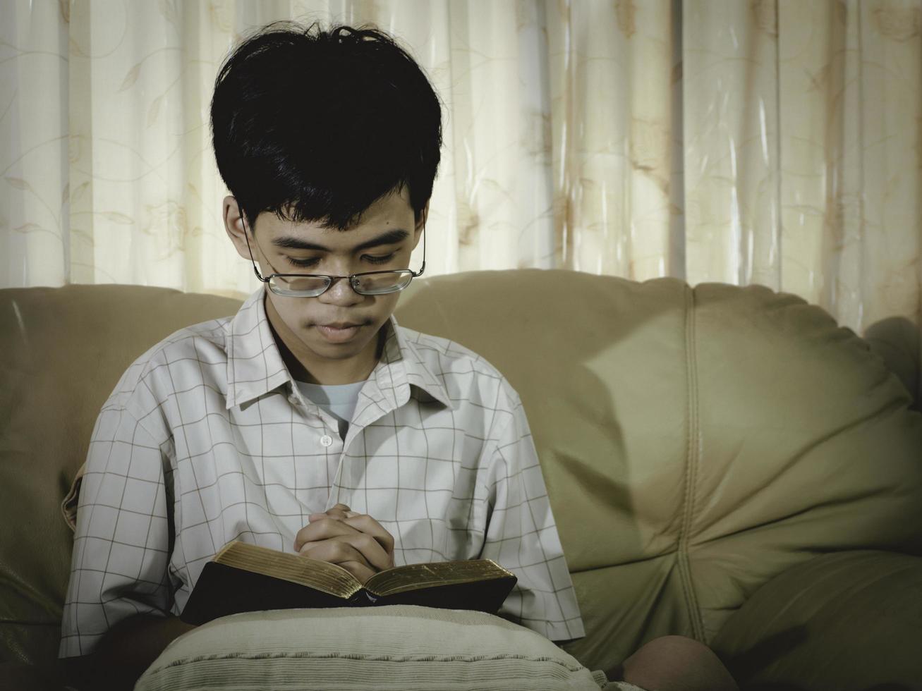 Asian young pray for god blessing to wishing have a better life with his hands on the bible in Christian church. And praying in worship room. Holding hands in prayer on bible. photo