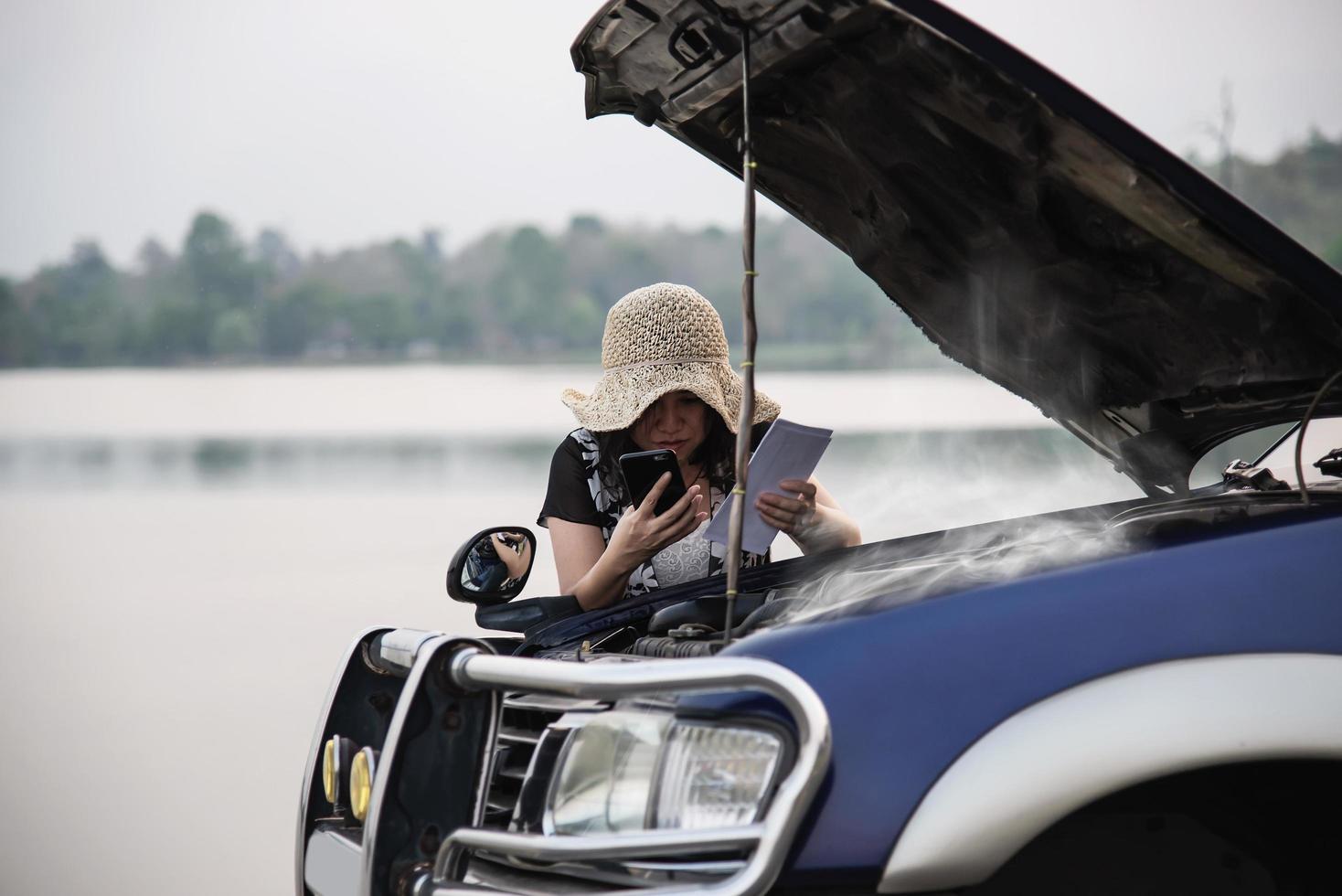 mujer asiática que llama al reparador o al personal de seguros para solucionar un problema de motor de camión en una carretera local - personas con concepto de transporte de problemas de camión foto