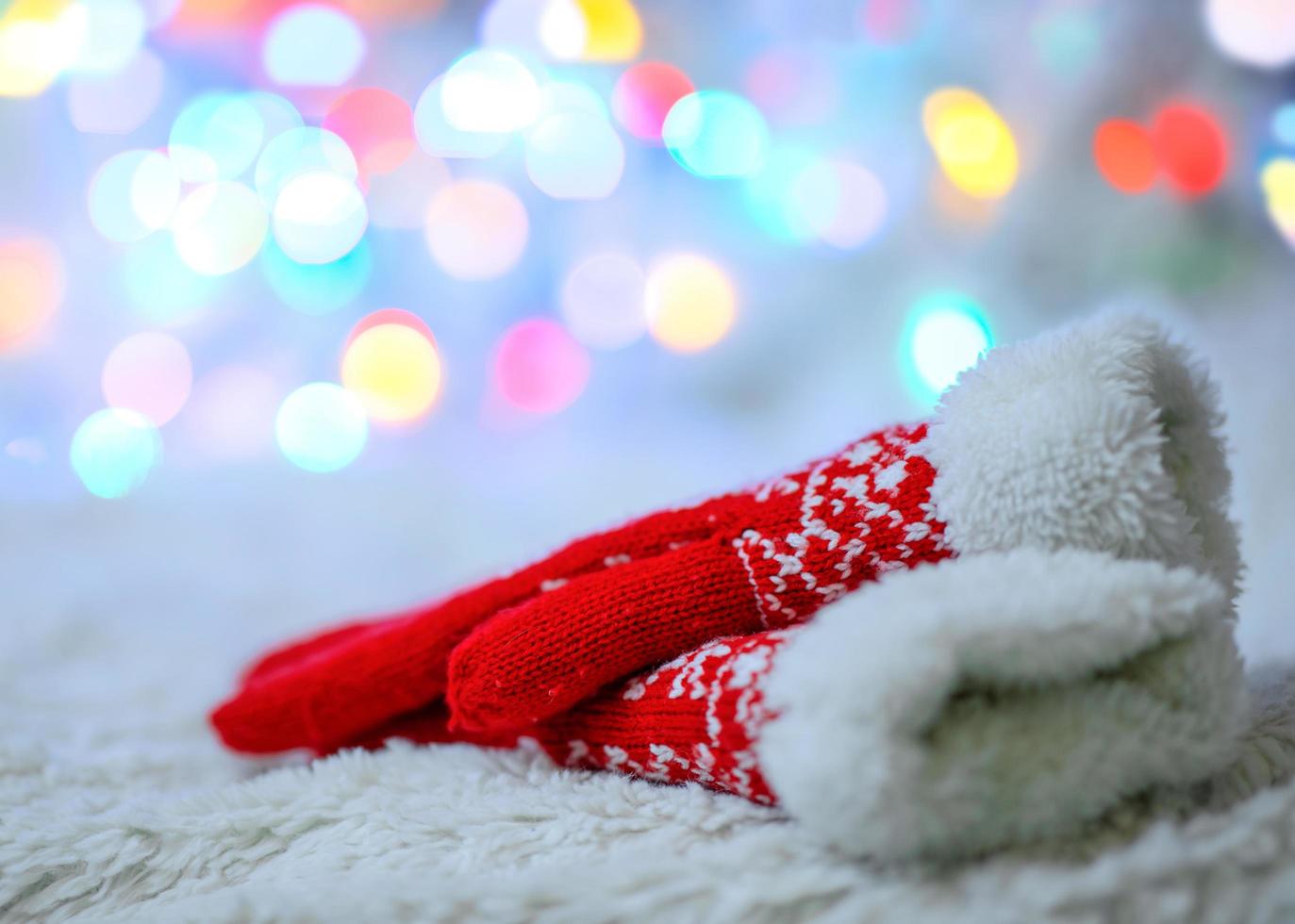 Red wool mittens on a white background and bokeh. Winter mood photo