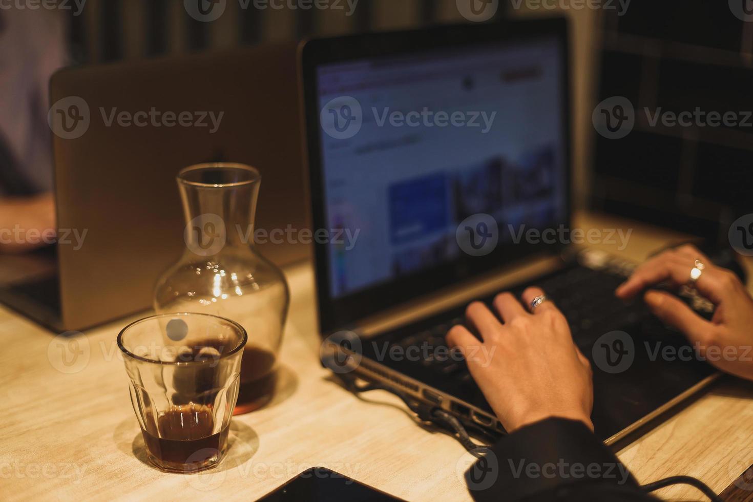 Female using her laptop at a cafe. Closeup shot of woman sitting at a table with a cup of coffee and surfing the net on her laptop computer. photo