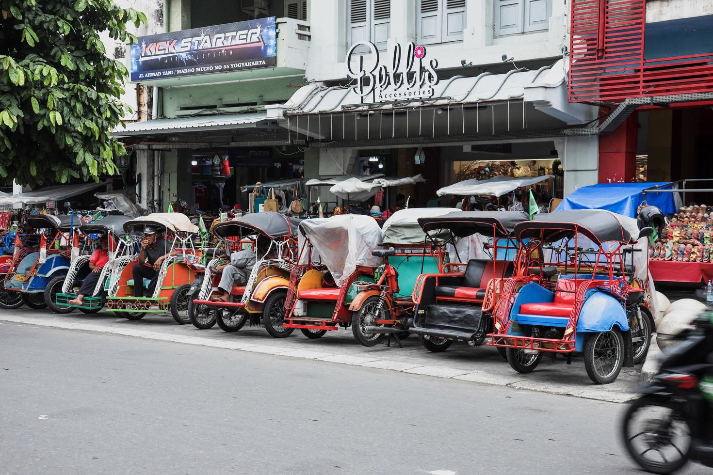 yogyakarta, indonesia - mayo de 2022 becak estacionado en el lado de la carretera de la calle malioboro. becak es un rickshaw o triciclo local, transporte tradicional de indonesia. foto