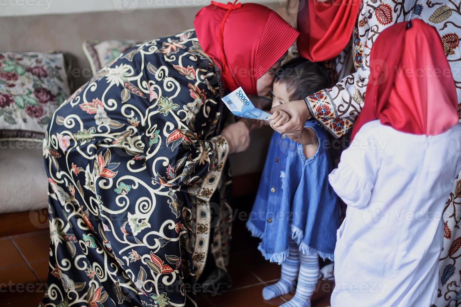 Grandmother kissing granddaughter during lebaran idul fitri day. photo