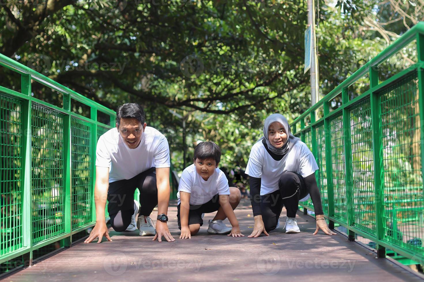 Sporty muslim mother father and son getting ready to run in a crouch start position. Outdoor sports and fitness family. Running and jogging. photo