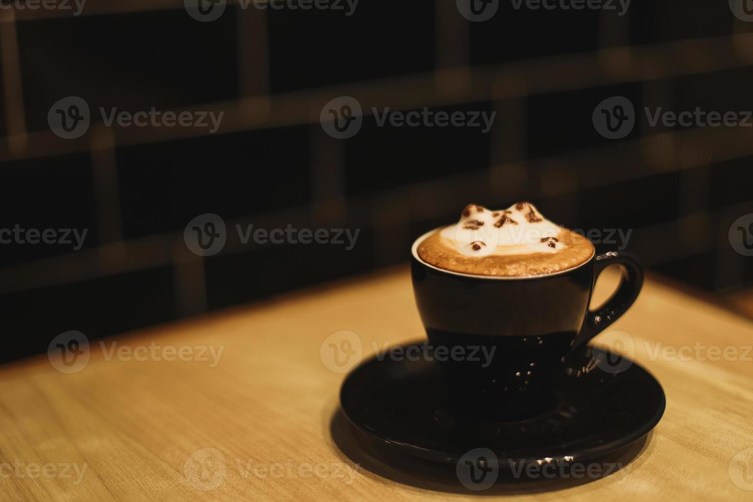 A cute cat hot latte art on cappuccino coffee mug under a dim light photo