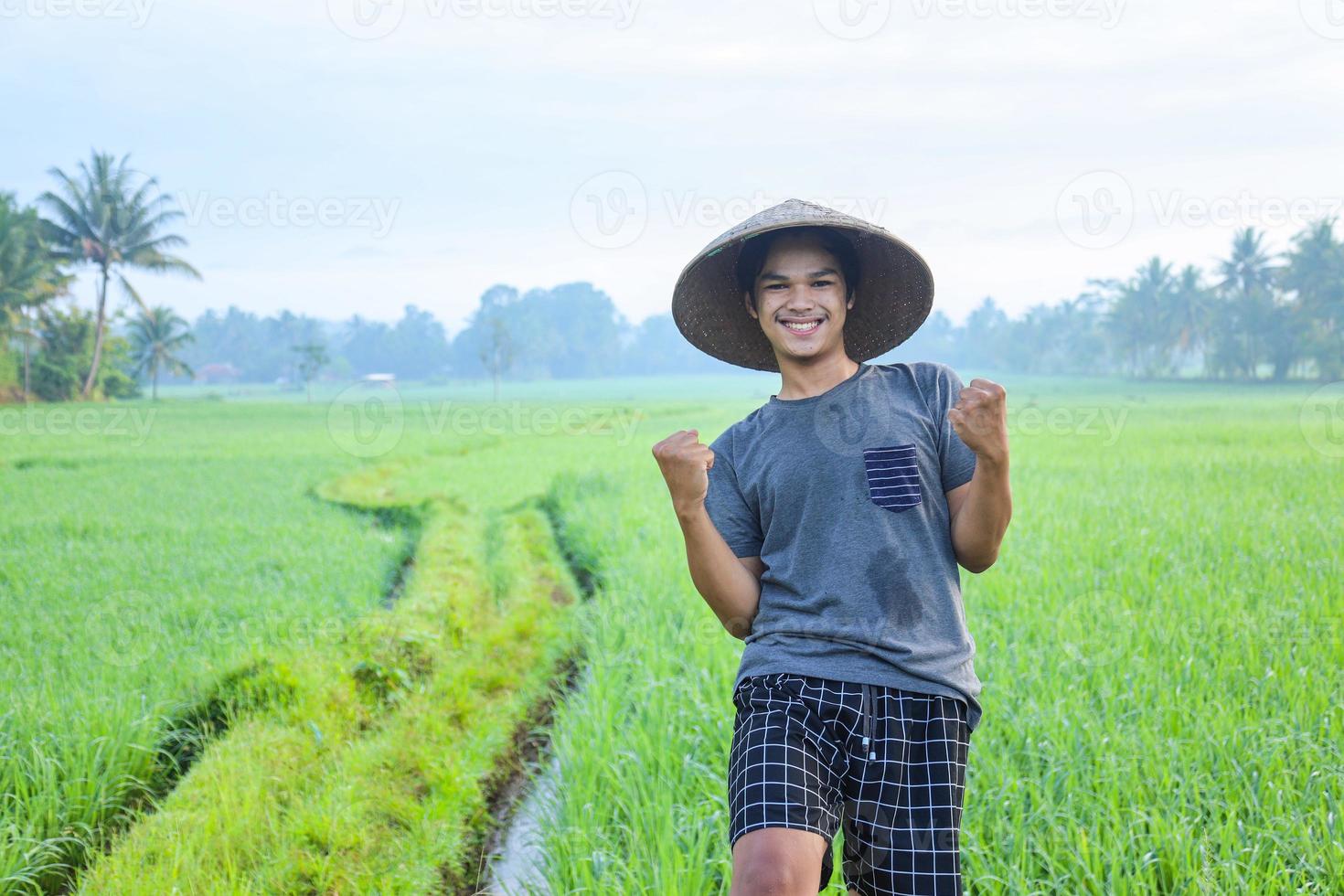 Close-up of attractive cheerful young Asian farmer rejoicing having success attainment to growing paddy rice at the rice field. Modern agriculture concept. photo