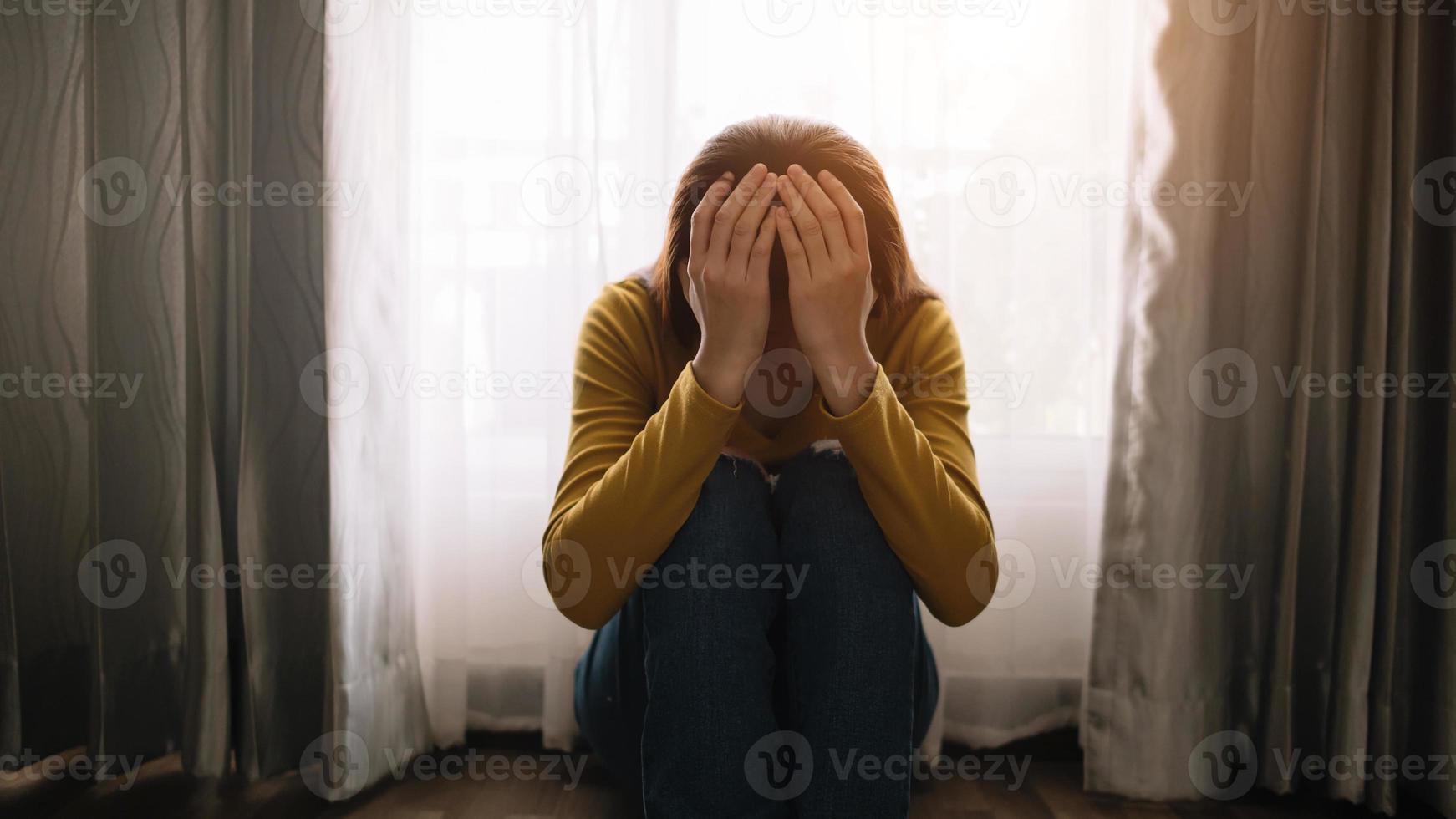 la mujer se sienta depresión de pie junto a la ventana y la ansiedad copia el espacio. foto