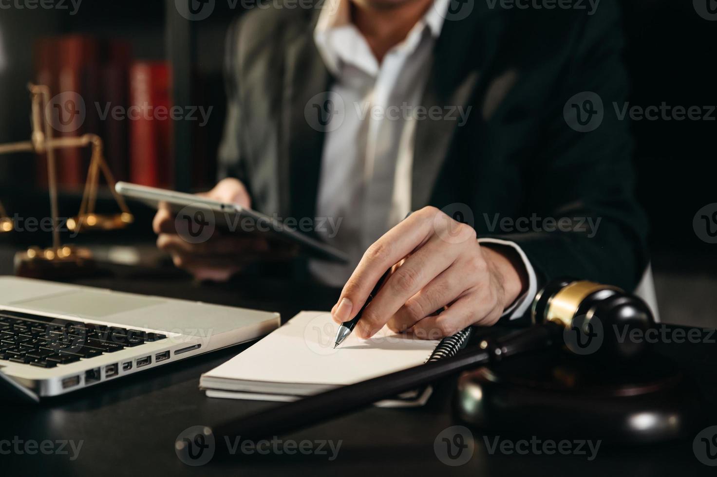 Justice and law concept.Male judge in a courtroom with the gavel, working with, tablet computer photo