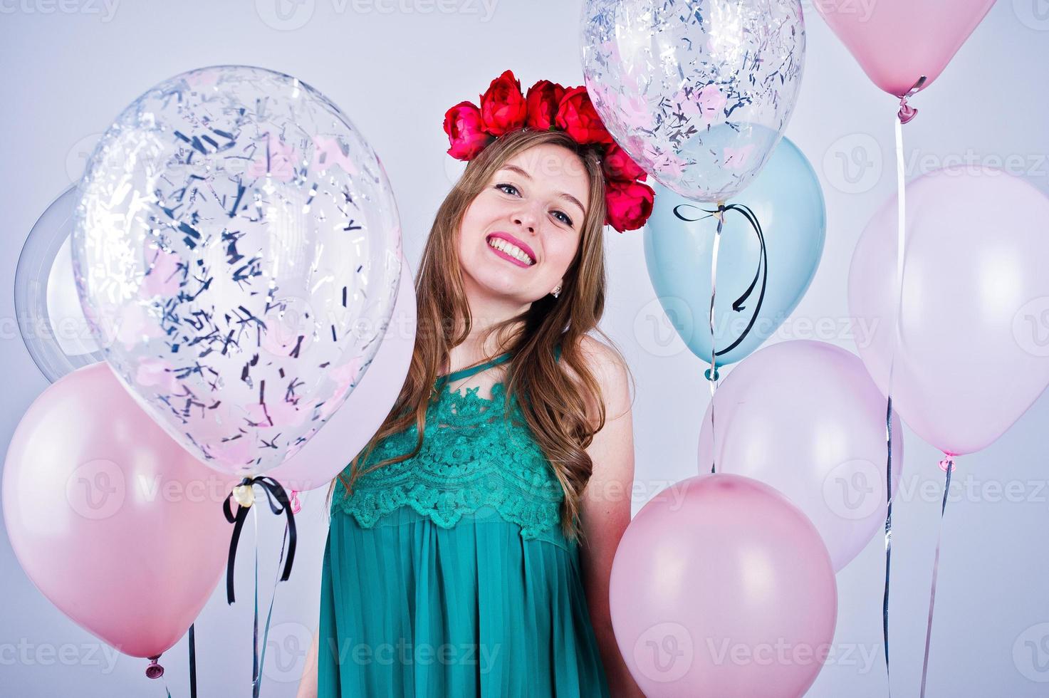 Happy girl in green turqoise dress and wreath with colored balloons isolated on white. Celebrating birthday theme. photo