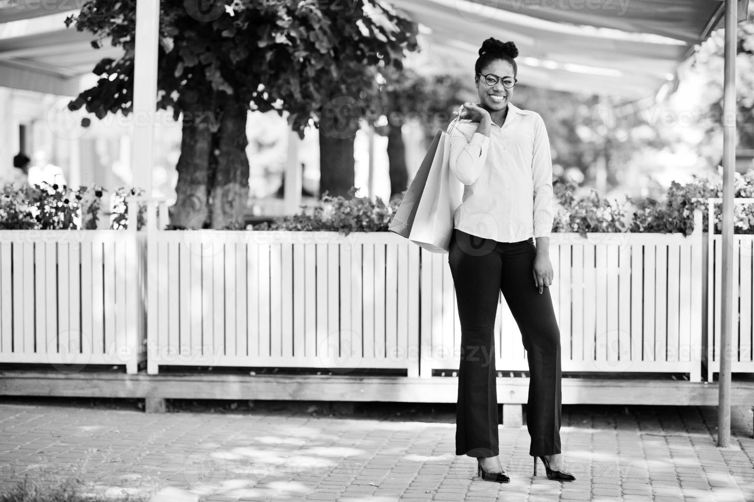 Casual african american girl with colored shopping bags walking outdoor. Stylish black woman shopping. photo