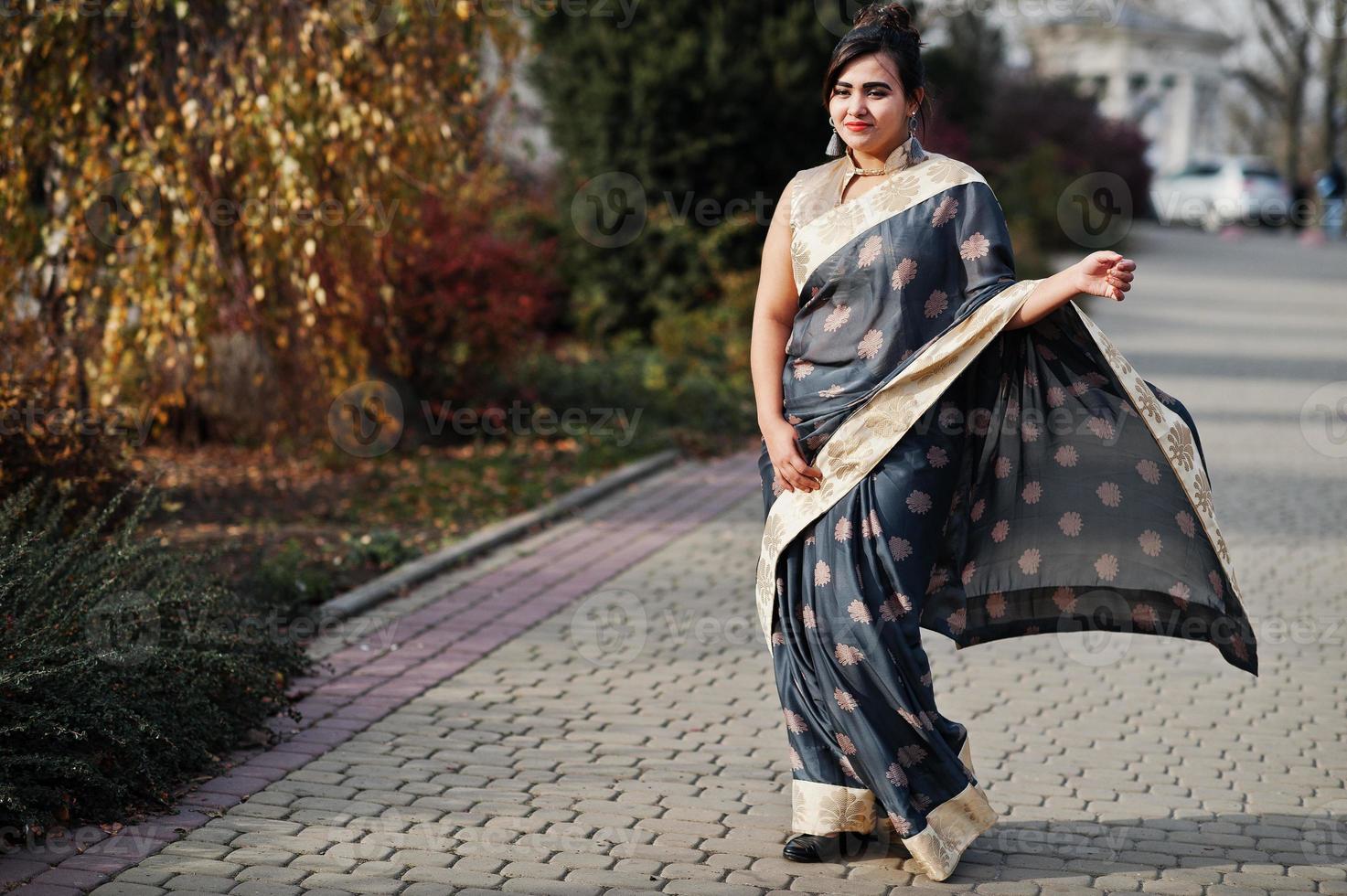 Elegant brunette south asian indian girl in saree walking outdoor. photo