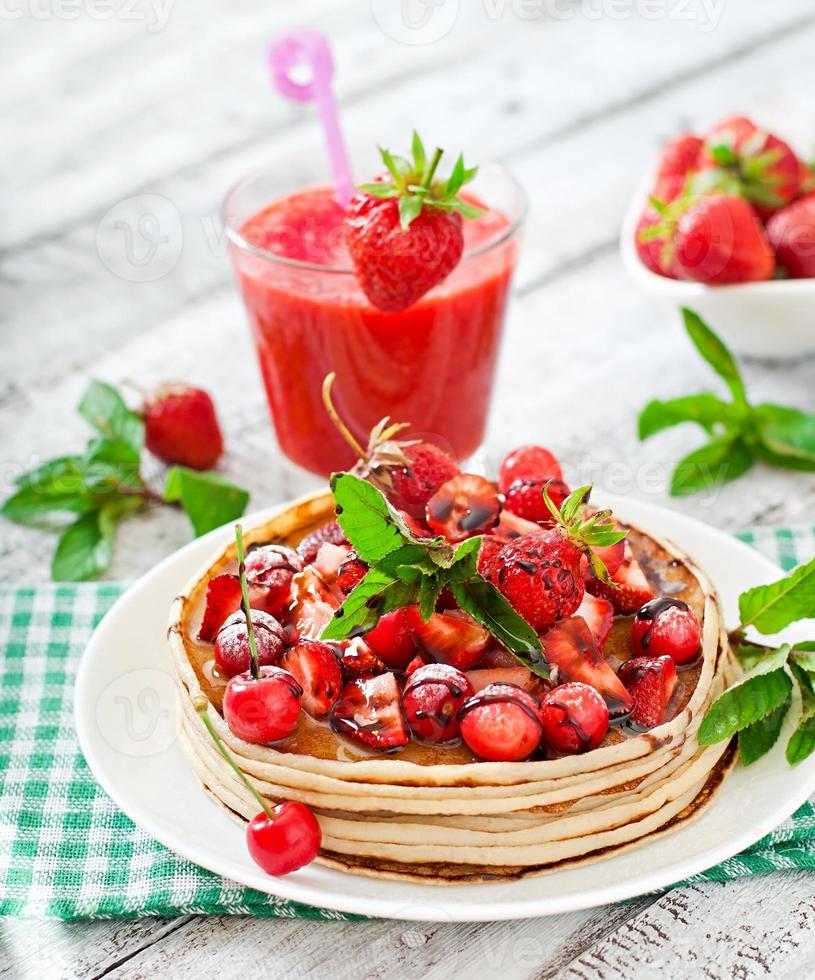 Pancakes with berries and strawberry smoothie in a rustic style photo