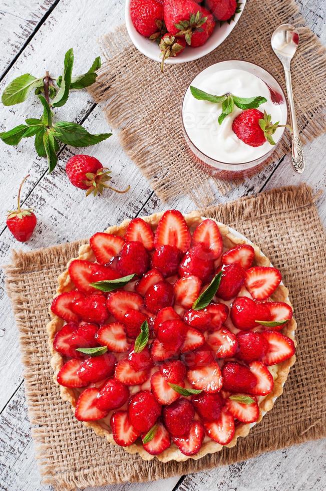 Tart with strawberries and whipped cream decorated with mint leaves photo