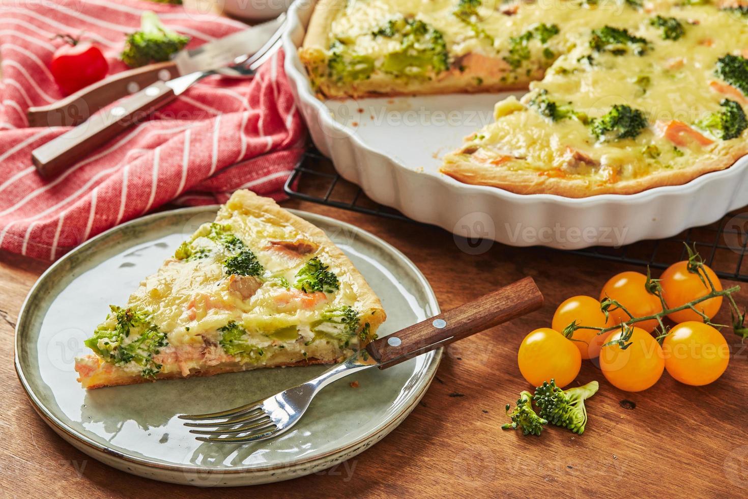 Homemade quiche with red fish, salmon, broccoli and cheese on wooden background photo
