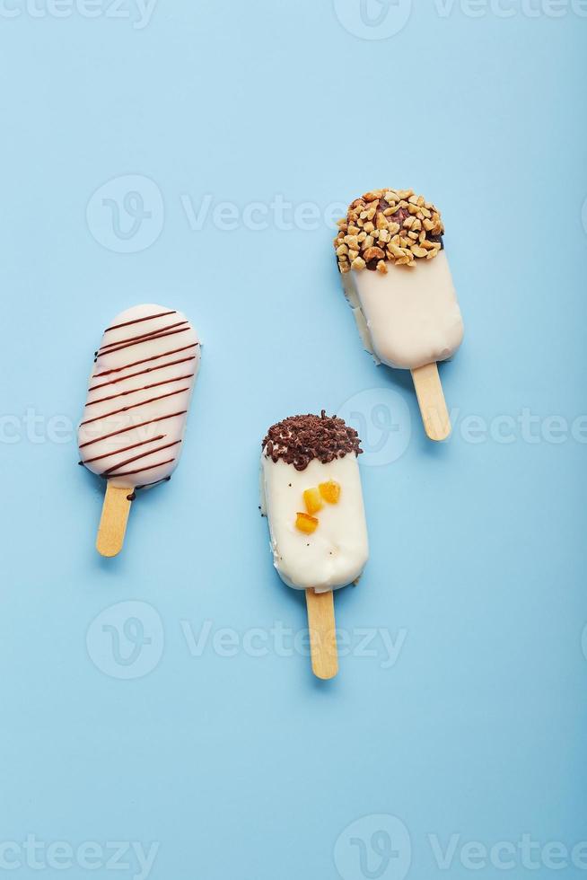 Mousse dessert with fruit flavors in the form of popsicle ice cream on blue background. photo