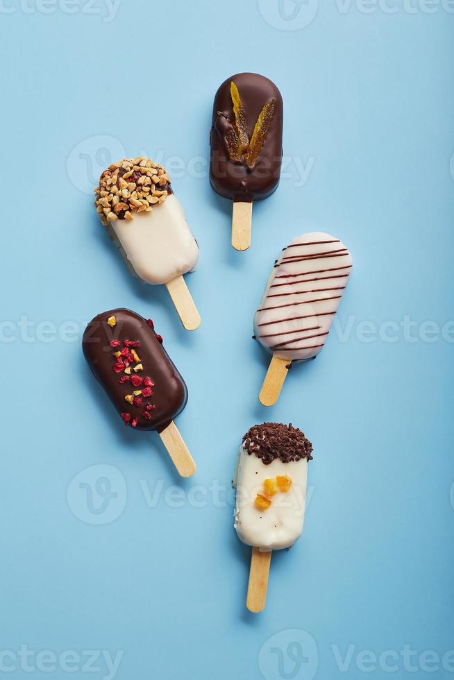 Mousse dessert with fruit flavors in the form of popsicle ice cream on blue background. photo