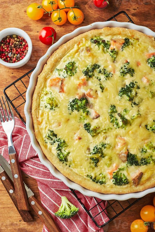 Homemade quiche with red fish, salmon, broccoli and cheese on wooden background photo