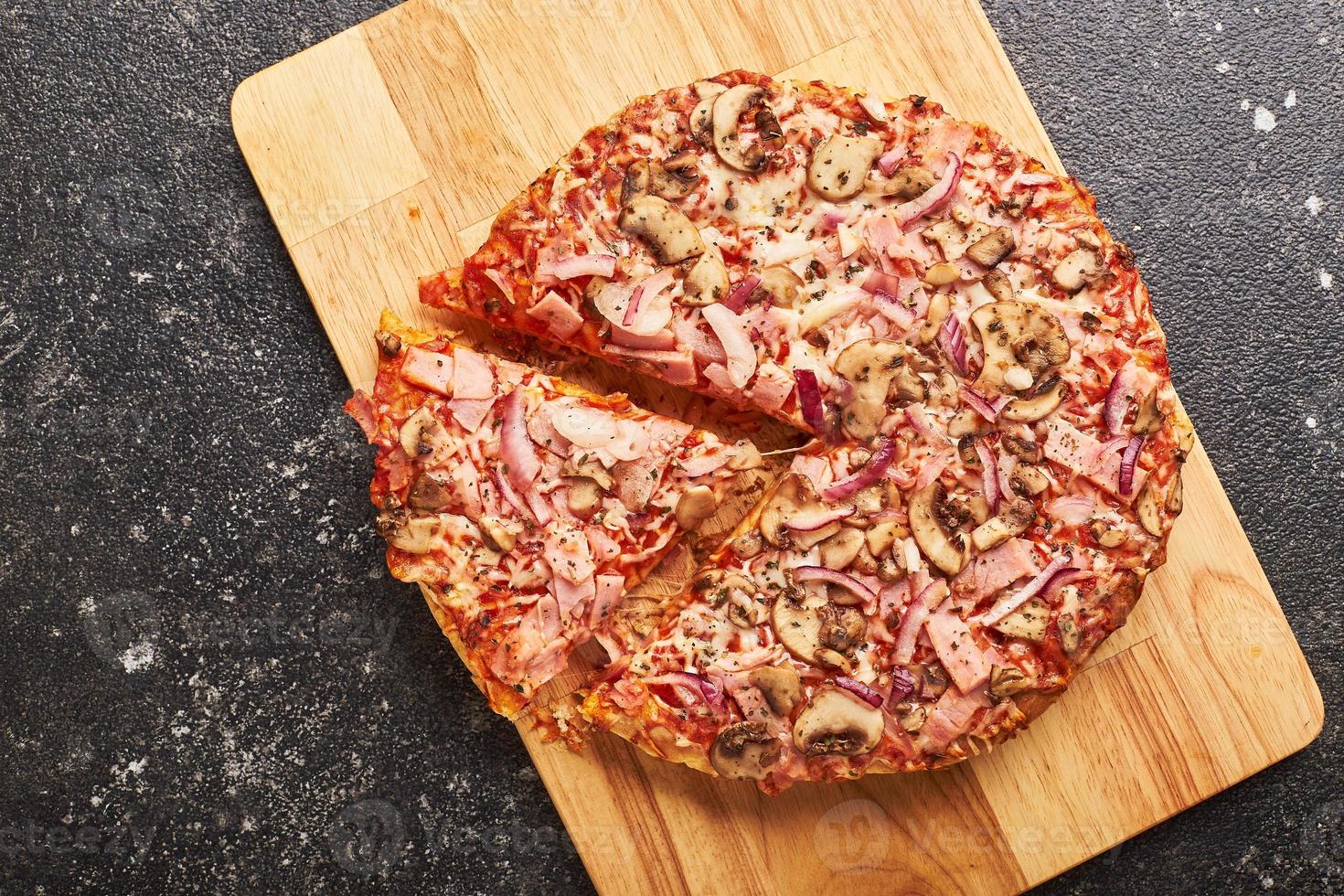 Fast food, Baked frozen pizza with ham, mushrooms and cheese on thick dough. Ready to eat. photo