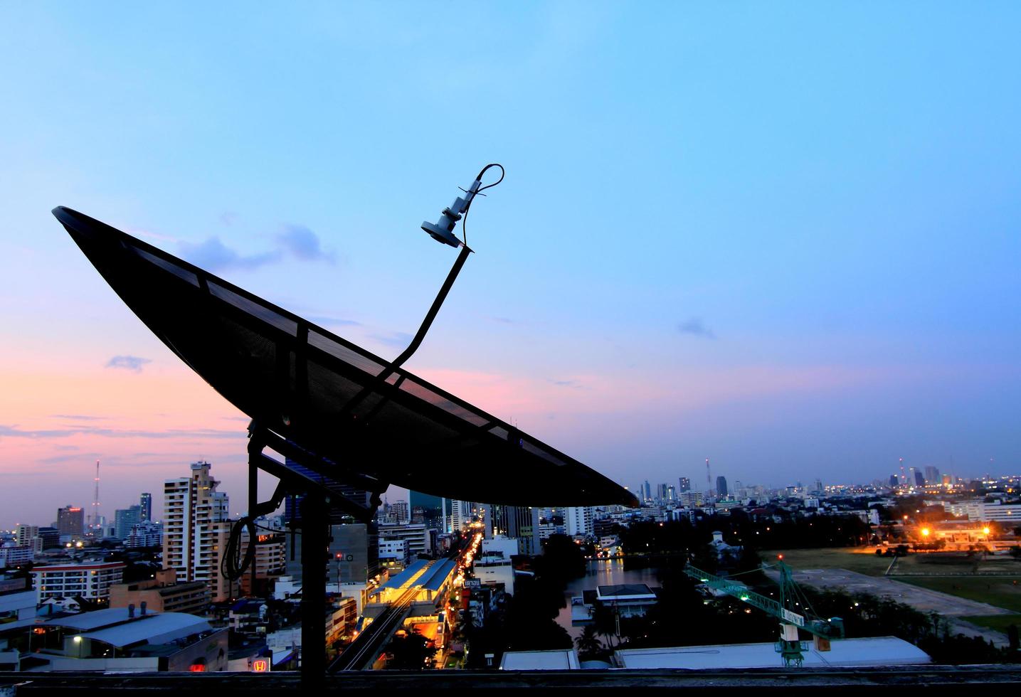 antena parabólica de comunicación de antena negra sobre el cielo del atardecer en el paisaje urbano foto