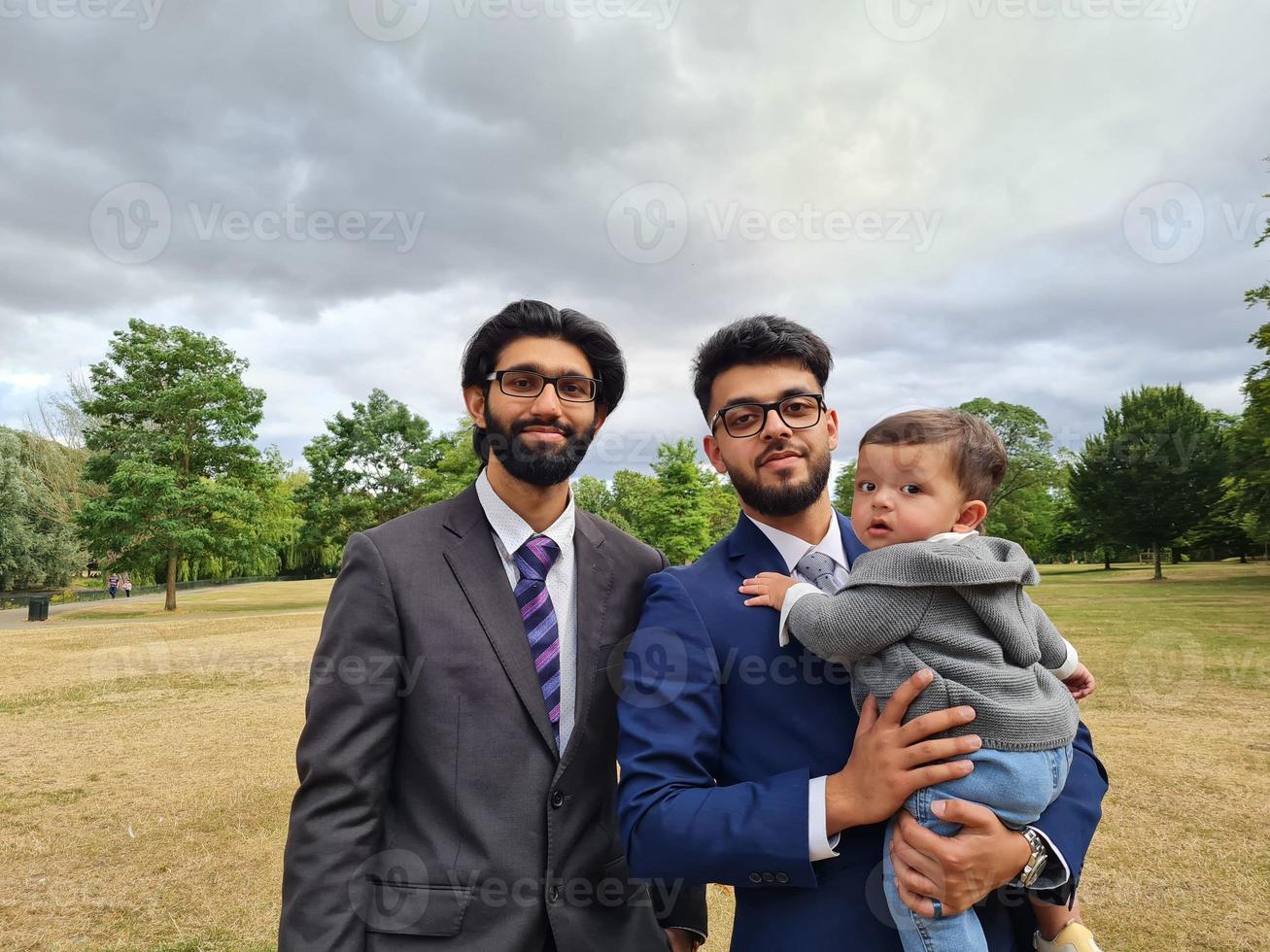 2 Young Asian Males are Walking with an Infant Baby Boy at Local Public Park of Luton England UK photo