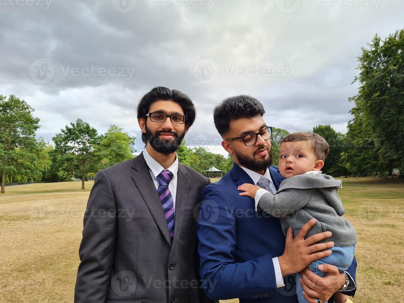 2 Young Asian Males are Walking with an Infant Baby Boy at Local Public Park of Luton England UK photo