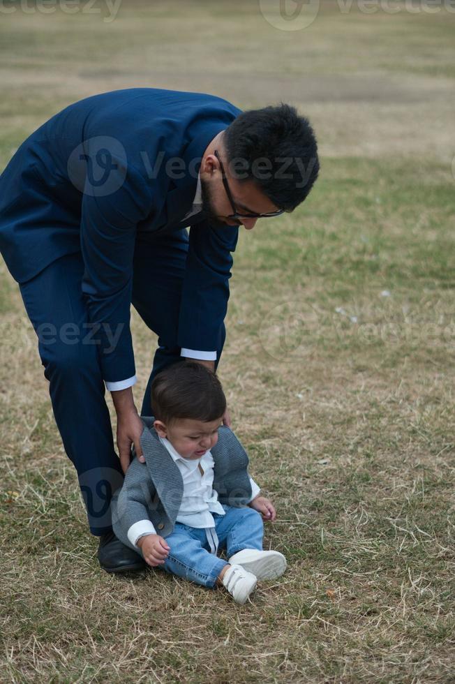 padre pakistaní asiático sostiene a su bebé de 11 meses en el parque local foto