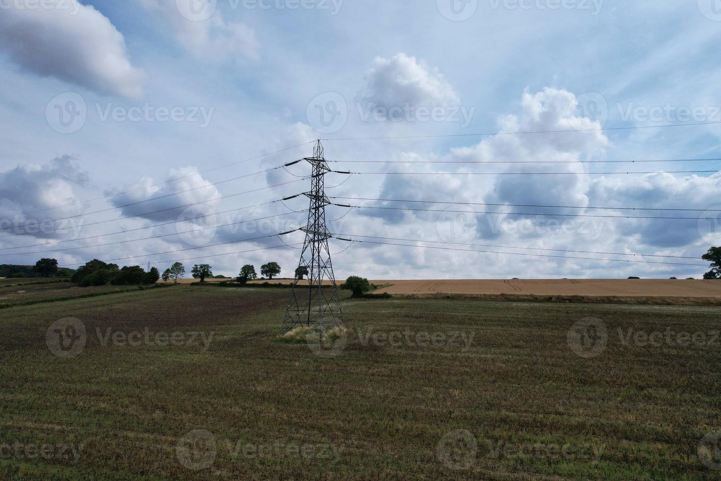High Voltage Power Supply Poles with Cables Running Through British Farmlands and Countryside, Aerial high angle view by drone's camera. photo