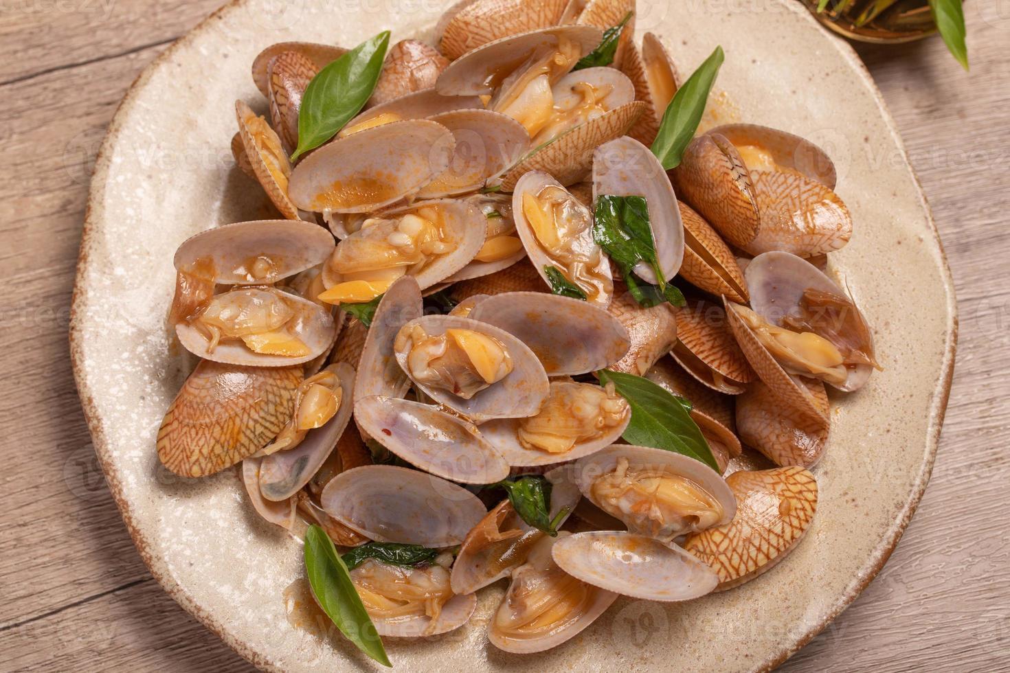 Stir fried clams with basil leaves in a white bowl photo