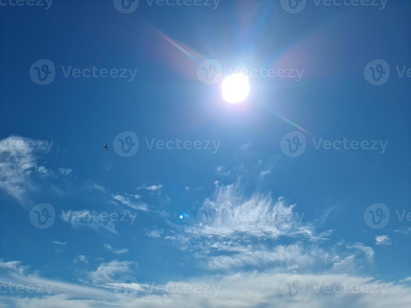 hermosa vista a los rayos de sol con algunas bengalas y nubes en un cielo azul foto