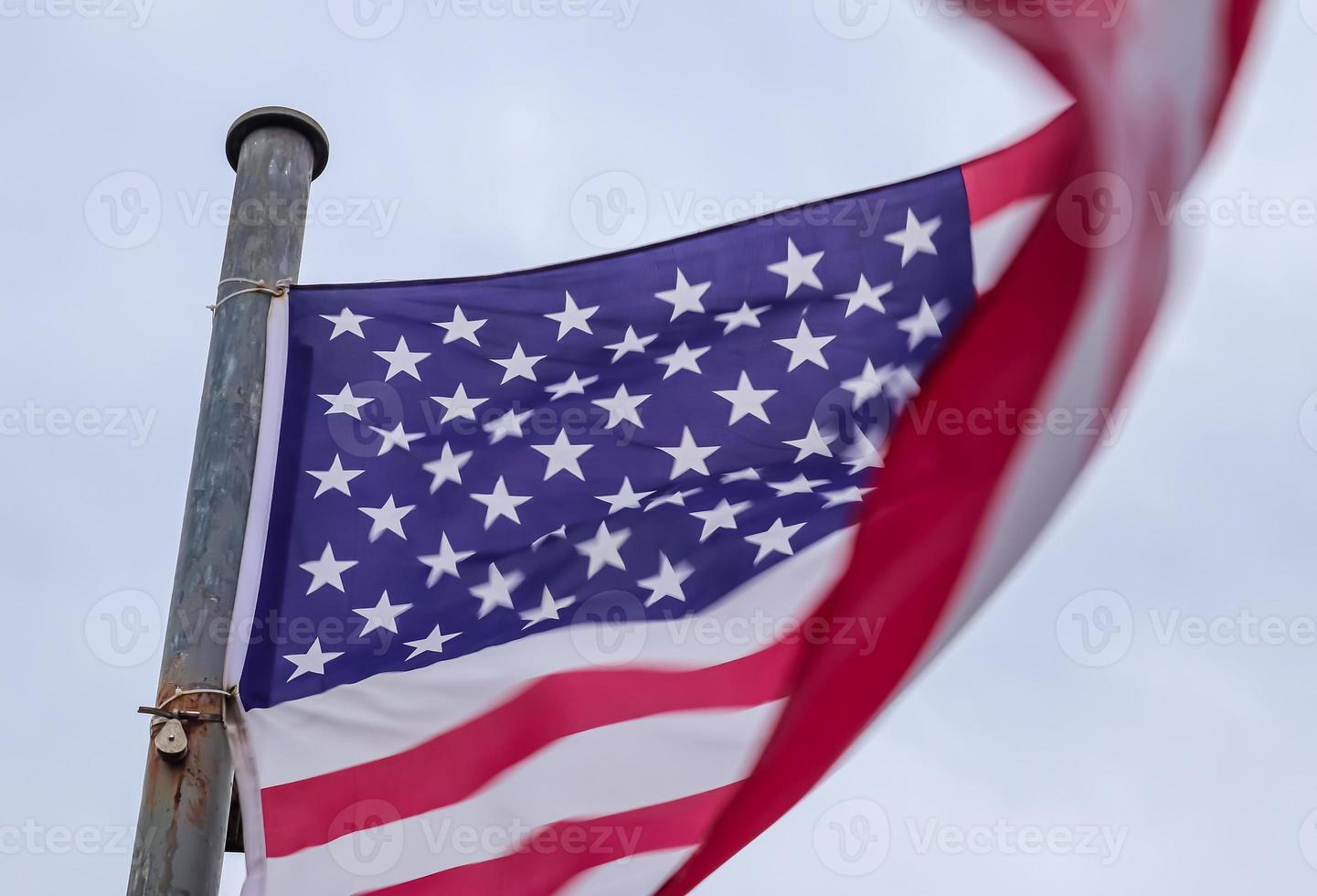 bandera de estados unidos en un asta de bandera moviéndose lentamente en el viento contra el cielo foto