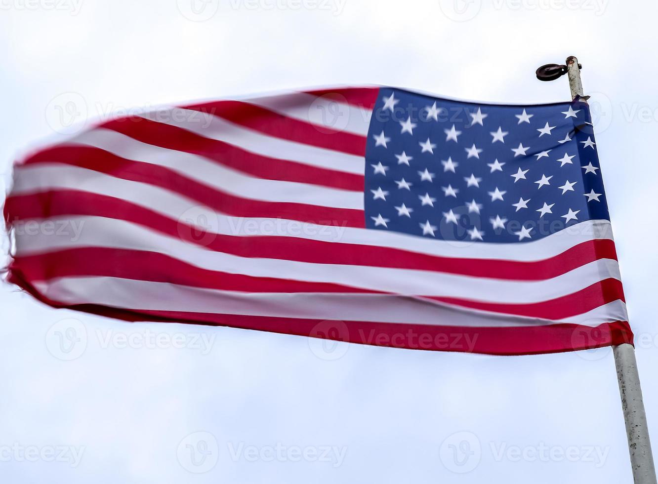 bandera de estados unidos en un asta de bandera moviéndose lentamente en el viento contra el cielo foto