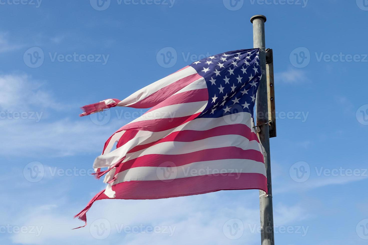 USA flag at a flagpole moving slowly in the wind against the sky photo
