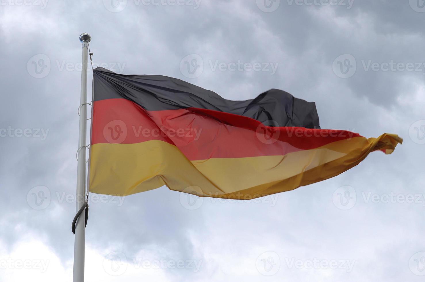 bandera de alemania en un asta de bandera moviéndose lentamente en el viento contra el cielo foto