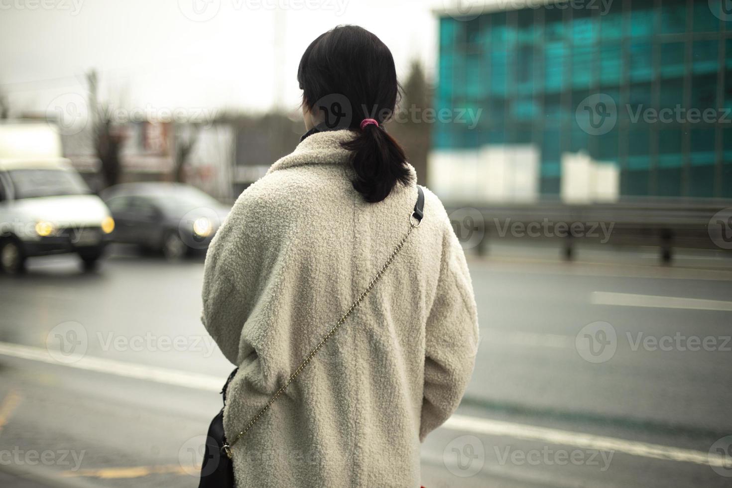 Girl is waiting for transport by road. Woman stands on highway. photo