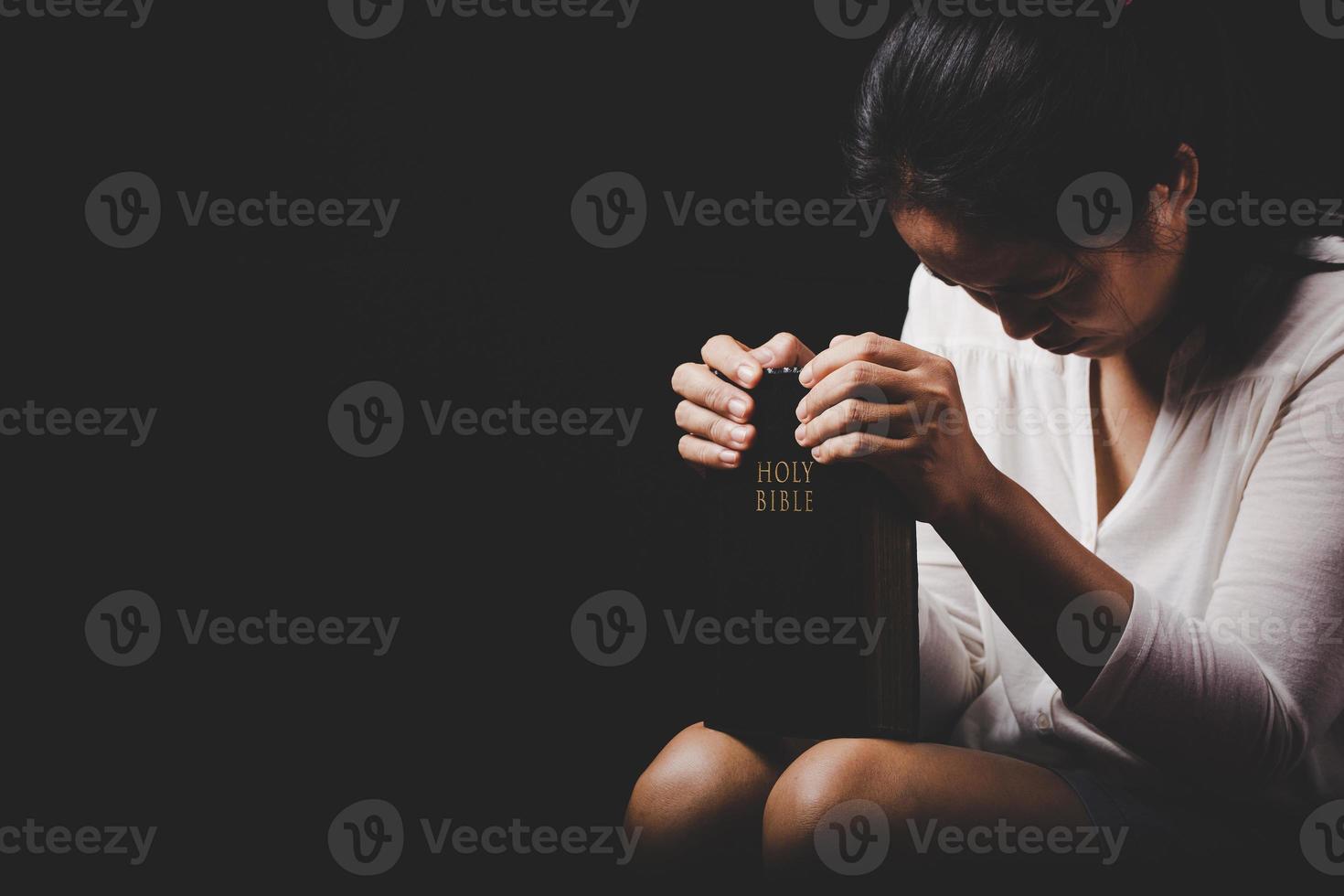 christian woman hand on holy bible are pray and worship for thank god in church with black background, concept for faith, spirituality and religion photo